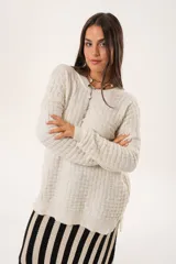 Buzo oversize color beige confeccionado en tejido sintético con destellos de lurex, cuello redondo y manga larga.