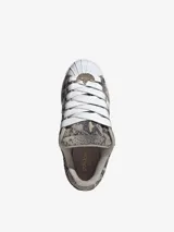 Zapatillas Adidas Superstar ST con exterior de diseño texturizado símil animal print de serpiente en tonos grises y tostados, combinados con las icónicas tres tiras blancas, cordones anchos y la clásica puntera de caucho en color blanco.