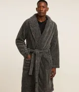 Bata de baño gris confeccionada en plush con textura acanalada. Tiene lazo en la cintura y bolsillos delanteros.