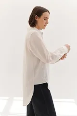 Camisa color crema de lyocell con cuello clásico, cierre frontal con botones, bolsillo de parche en el pecho y pespuntes a contraste en negro.