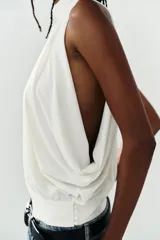 Top halter blanco de diseño fluido con frunces en el cuello, mangas murciélago y bajo con acabado tipo globo.