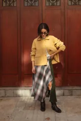 Falda midi de diseño asimétrico que combina un panel de tela escocesa en tonos verdes, blancos y marrones con un panel lateral de paño verde oscuro. Presenta un tajo lateral pronunciado y tiro a la cintura.