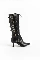 Botas altas de cuero negro con acabado brillante texturado, múltiples tiras con hebillas y tachas plateadas, cordones frontales, punta fina y taco bajo escultural.