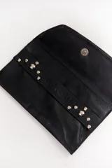 Sobre de cuero negro con solapa, cierre magnético y muñequera con tachas plateadas.