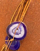 Collar con dije de piedra ágata en tonos morados suspendido de un tiento de cuero.