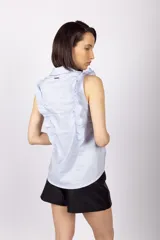 Blusa celeste sin mangas con cuello camisero y volados en los hombros.