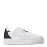 Championes urbanos Puma modelo Shuffle Downtown, color negro con detalles en dorado. Presentan una capellada de cuero sintético con perforaciones en la puntera, cierre de cordones y suela de goma vulcanizada.