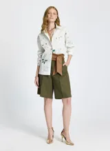 Camisa de manga larga con estampado floral y de texto, con cuello clásico, cierre frontal con botones y lazo ajustable en la cintura.