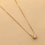 Collar de cadena fina tipo veneciana con dije de punto de luz circular, elaborado en plata 925 con baño de oro y engastado con una circonia central.