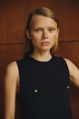 Vestido corto azul marino, de corte recto y sin mangas, con escote redondo y cierre oculto en la espalda. Tiene cuatro bolsillos de parche con botón dorado. Está forrado.