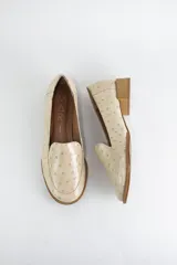 Mocasin de cuero con textura símil avestruz en color suela, con punta redonda y taco bajo cuadrado símil madera.