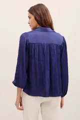 Camisa de poliéster color azul, de corte holgado, con mangas largas y puños elásticos.