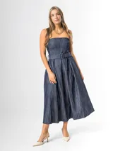 Vestido midi strapless de denim azul, con escote recto, espalda elastizada y falda amplia con pliegues. Incluye un cinto del mismo material con hebilla.