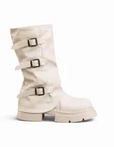 Bota tipo biker de caña media en color beige, con diseño de polaina superpuesta y tres correas horizontales con hebillas metálicas negras. Presenta una suela track gruesa y robusta del mismo tono.