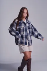 Sobrecamisa de franela color beige con estampado a cuadros en tonos marrones y azules, de corte holgado, con cuello clásico, cierre abotonado y bolsillos delanteros con solapa.