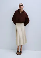 Falda midi color beige claro con diseño de tablas encontradas y corte en A.