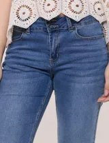 Jean de denim azul con elasticidad confortable, tiro medio, cierre frontal con cremallera y doble botón metálico. Cuenta con diseño de cinco bolsillos y corte bootcut, ajustado en muslos con un sutil ensanchamiento hacia el ruedo.