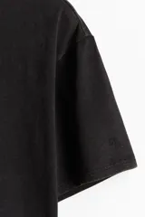 Remera deportiva negra de corte holgado con cuello redondo y mangas cortas. Tejido funcional DryMove™ con efecto lavado.