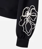 Saco de algodón color negro con cuello redondo y diseño de bordado floral en color blanco en el frente y las mangas.