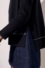 Sweater negro de cuello alto con tajos laterales y detalle de línea plateada en puños y ruedo.