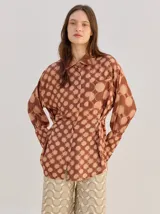 Camisa de algodón liviano y fresco con estampado geométrico estilo op art y retro en tonos marrones y beige, diseño holgado, manga larga, cuello camisero y bolsillo cuadrado en el pecho.