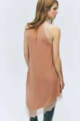 Vestido midi sin mangas de punto suave, con escote redondo y bajo asimétrico. Presenta detalles de encaje en las sisas, en la parte frontal y en el ruedo.
