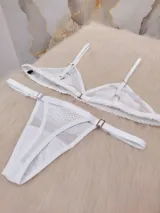 Conjunto de lencería compuesto por un corpiño triangular de microtul transparente con detalles de encaje floral en las copas y una tanga regulable con elástico ancho.