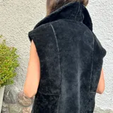 Chaleco negro de cuero ovino con cuello grande de cuero liso.
