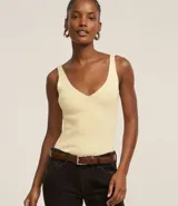 Blusa sin mangas de punto acanalado color crema, con escote en V y espalda descubierta. Confeccionada en una mezcla de viscosa y poliamida, presenta un ajuste al cuerpo y textura vertical en relieve.