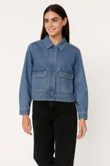 Campera corta de jean azul con cuello clásico, cierre frontal con botones a presión, dos bolsillos con solapa en el pecho y mangas largas con puños abotonados.