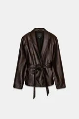 Chaqueta de Zara Woman Collection confeccionada en tejido efecto piel con textura granulada. Presenta cuello solapa, manga larga y cierre frontal con cinturón ajustable mediante lazada. Incluye forro interior.