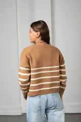 Saco de punto con cierre frontal, diseño a rayas horizontales negras sobre base color crema, de manga larga y calce holgado.