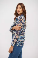 Camisa de manga larga con cuello clásico y cierre frontal de botones. Presenta un estampado abstracto en tonos azules, beige y marrón oscuro, con un corte holgado y fluido.