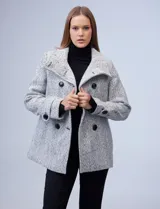 Tapado corto de lana y poliéster, con tejido tweed en tonos blanco y negro. Presenta cuello con solapa, doble abotonadura frontal en color negro y bolsillos verticales.