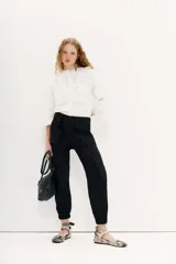 Pantalon cargo negro de calce relajado con ajuste en los tobillos. Cuenta con bolsillos laterales con solapa y cintura con cierre, botón y elástico en la parte posterior.