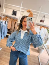 Buzo tipo chomba de corte oversize con diseño a rayas horizontales celestes y blancas. Presenta cuello camisero blanco y un bordado en la espalda con la inscripción República Oriental del Uruguay.