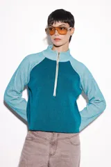 Sweater verde con cierre al cuello, de corte holgado y mangas largas.