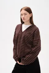 Sweater de punto a rayas horizontales color marrón y blanco, con cuello en V, capucha con cordones y cierre frontal parcial con botones. Presenta un diseño de manga larga con caída de hombros.