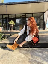 Chaleco negro con interior de corderito, con detalles en color naranja y ribeteado en marrón.