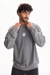 Buzo gris con efecto lavado, cuello redondo, mangas largas y un pequeño parche bordado en el pecho con la leyenda "Find Joy".