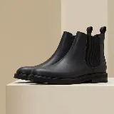 Bota tipo Chelsea de cuero vacuno color negro, con elásticos laterales y suela plana de goma.