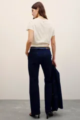 Pantalón sastrero de denim azul oscuro con costuras pespunteadas a contratono. Cuenta con cierre metálico frontal, gancho sastrero y botón en la cintura.
