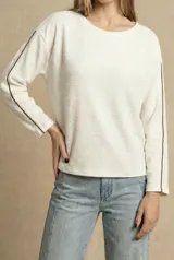 Sweater de corte oversize color crema, con textura acanalada horizontal y detalle de línea vertical oscura a lo largo de las mangas. Presenta cuello redondo y mangas largas.