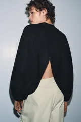Top corto negro de punto fino, con cuello redondo y mangas largas abullonadas con pliegues.