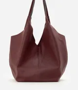 Cartera hobo grande marca Satinato, confeccionada en cuero con textura natural y color marrón oscuro. Presenta un diseño amplio y suave de estilo contemporáneo, con asas de hombro integradas y cierre interno con mosquetón.