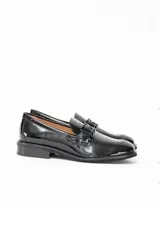 Mocasín de mujer en cuero charol negro, con diseño clásico de punta redondeada y detalle de herraje metálico en el empeine. Cuenta con suela plana y tacón bajo.