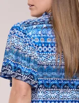 Blusa estampada en tonos azules con escote en V y cuello con frunces. Tiene mangas cortas amplias estilo mariposa y corte recto a la cadera.