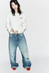 Camiseta de manga larga color blanco, corte regular fit, con cuello redondo y bajo recto. Presenta un pequeño texto estampado en color rojo en el pecho.