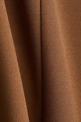 Pollera ajustada de punto color marrón, con tiro alto y elástico oculto en la cintura. Modelo a la rodilla con costuras visibles en el frente y tajo en la parte trasera.