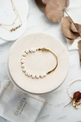 Pulsera dorada de acero quirúrgico con baño de oro 18k, decorada con perlas de agua dulce.